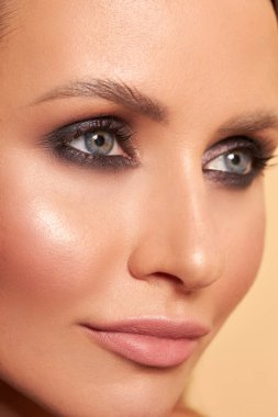 Güzel bir yüzü, makyajı ve sarı arka planda uzun siyah kirpikleri olan güzel bir kız.