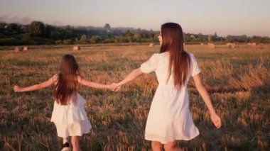 Anne ve kızı mutlu bir şekilde el ele tutuşup koşuyorlar.