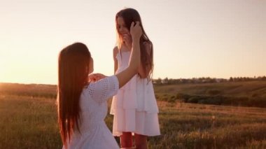 Genç bir anne gün batımına karşı tarlada kızının saçını okşar.