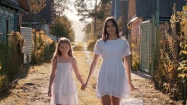 Anne ve kızı köyde yürüyorlar. Birbirlerine bakıp el ele tutuşuyorlar.