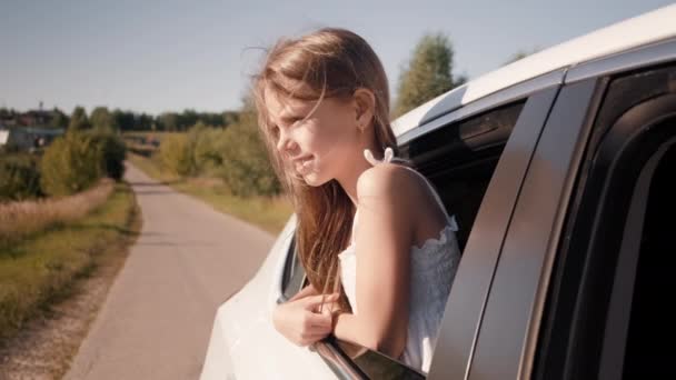 Ein Kind im Fenster eines fahrenden Autos. Ein Kind reitet auf dem Rücksitz vor der Kulisse sommerlicher Landschaften — Stockvideo
