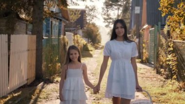 Anne ve kız el ele tutuşarak köyde dolaşıyorlar.