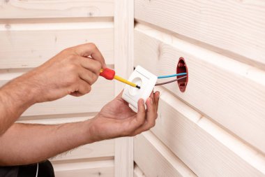 .Elinde bir closeup kesme bir soket yükleme elektrikçi.