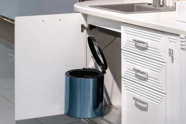 metal rubbish bin under sink hanging on kitchen cupboard door.