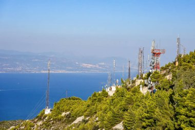 .Telekomünikasyon antenler deniz kenarında bir dağ kenarında.