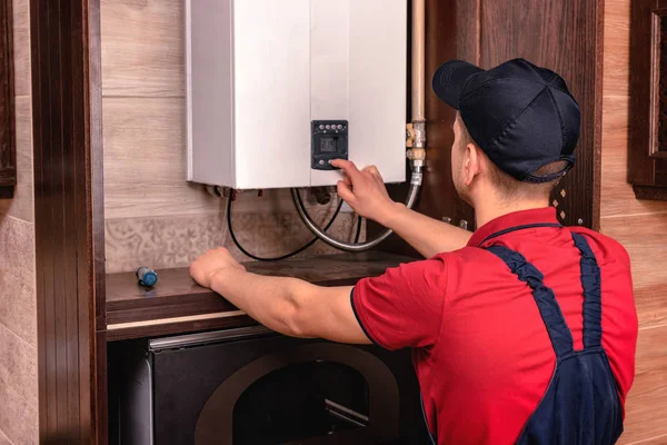 Plumber adjusts gas boiler before operating.