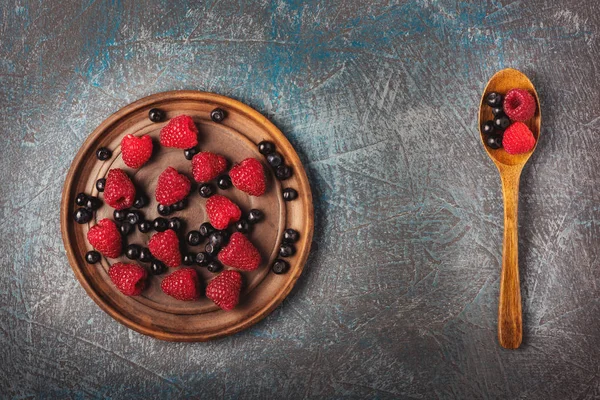 Yaban mersini ve ahududu gri beton zemin üzerine eski moda bir kap içinde