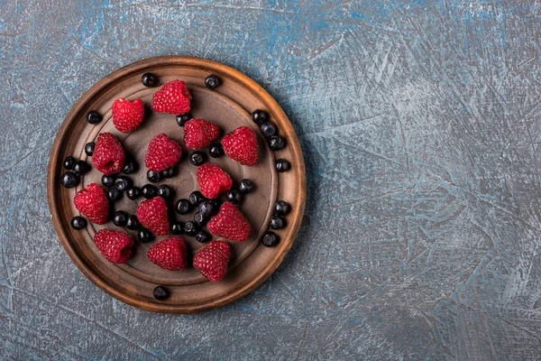 Yaban mersini ve ahududu gri beton zemin üzerine eski moda bir kap içinde