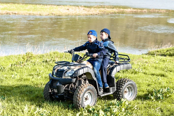Friends are traveling by quad bike along the river bank.