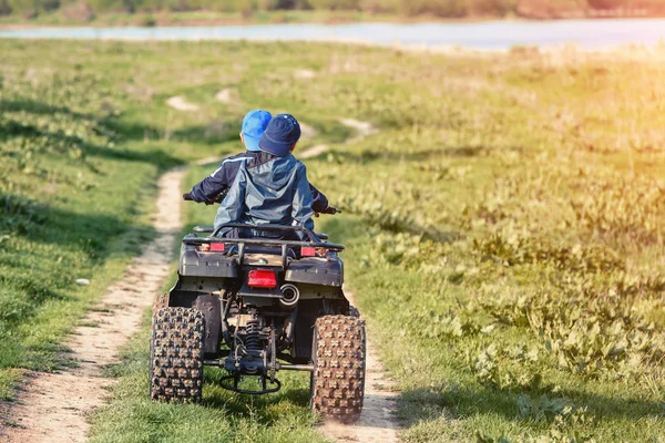 Friends are traveling by quad bike along the river bank.