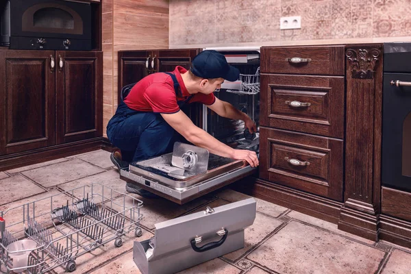 Młody mężczyzna technika naprawy zmywarkę do naczyń w kuchni — Zdjęcie stockowe
