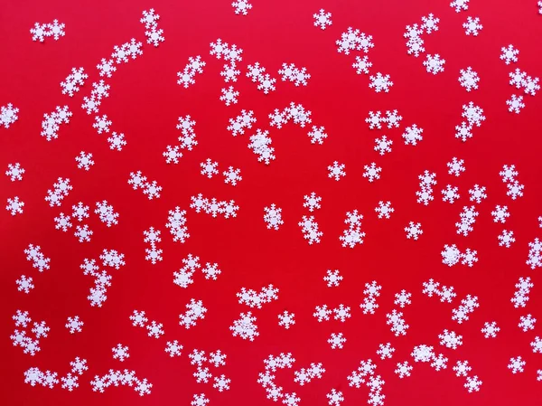 Flocos de neve brancos espalhados no fundo vermelho. Simples deitado plano festivo. Foto stock . — Fotografia de Stock