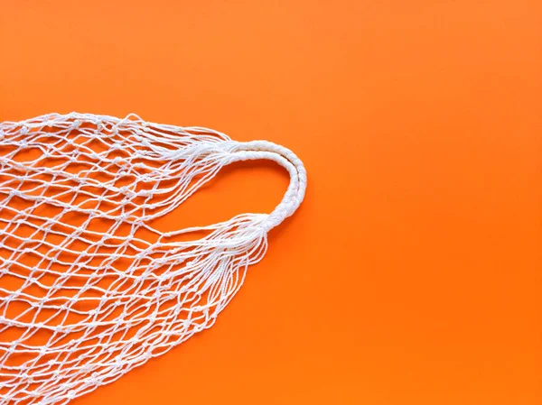 White string cotton eco bag on orange background. Simple flat lay with copy space. Ecology zero waste concept. Stock photo.