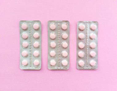 Pembe arka planda yumuşak pembe hapların kabarcıkları. Tek renkli, düz düz, pastel desenli. Tıbbi konsept. Stok fotoğrafçılığı.