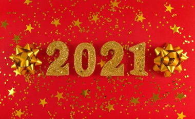 2021 yılının tebrik kartı. Kırmızı zemin üzerinde altın parıltılı figürler, yıldızlar ve fiyonklar.