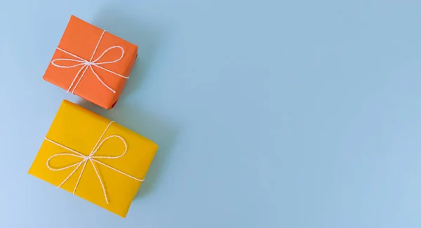 Cajas de regalo amarillas y naranjas sobre fondo azul. Plano simple con espacio de copia. — Foto de Stock
