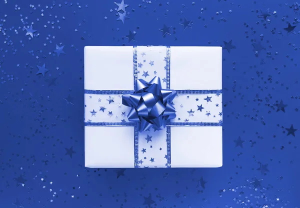 Scatola regalo e stelle su sfondo blu. Piatto monocromatico. — Foto Stock