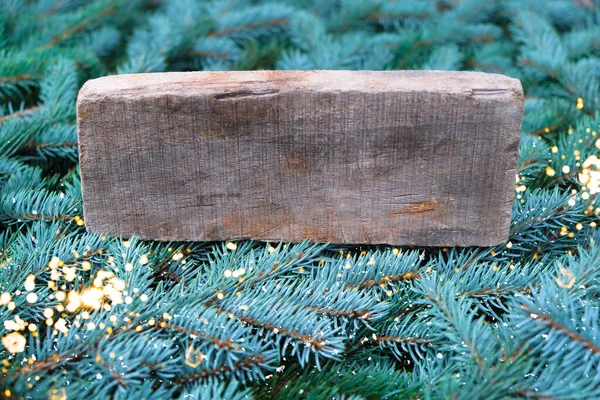 En gammal bräda på bakgrunden av grenar av en julgran. — Stockfoto