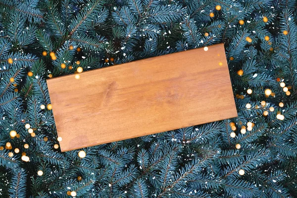 En gammal bräda på bakgrunden av grenar av en julgran. — Stockfoto