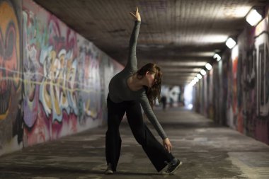 Kadın dansçı hareket kentsel bir tünelde gerçekleştirme. Tam uzunlukta. Seçici odak. 