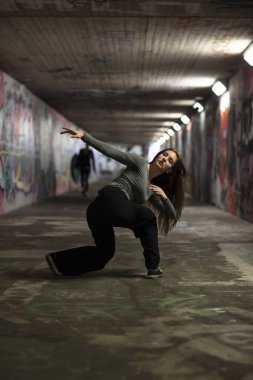 Kadın dansçı hareket kentsel bir tünelde gerçekleştirme. Tam uzunlukta. Seçici odak. 