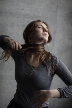 Kadın modeli zarif bakarken saçını boynuna bağlıyor. Orta atış. 