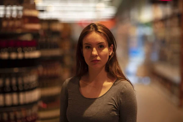 Portrait of a young woman standing in a supermarket aisle. Selective focus. Medium close up.