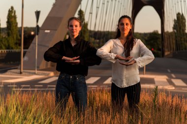 Dans ve şehir yolda predominating sıcak renkler ile poz iki genç kadın. Üç çeyrek uzunluğu. 