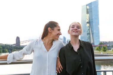 Şehir Köprüsü nehir üzerinde yan yana ve gülümseyerek duran kız. Orta atış. 