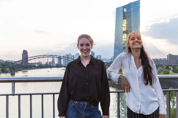 Two Young Women Posing Smiling City Bridge River Metropolis Skyline — Stock Photo, Image