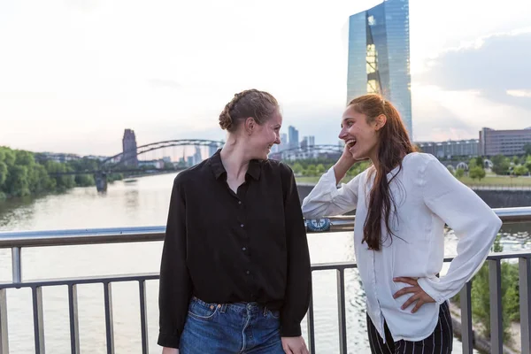Girlfriends Standing City Bridge River Looking Each Other Laughing Medium — Stock Photo, Image