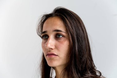 Yüz portre karma yarış genç bir kadın beyaz bir duvar önünde. Yan görünüm. 