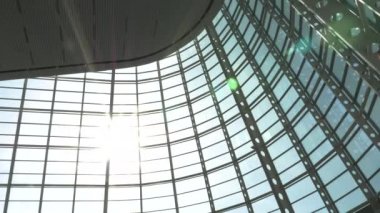 Günışığı modern bir cam binanın içinde parıldıyor.