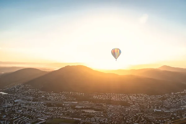Cityscape of Bergen, Norway with mountains and hot air balloon in sunshine. Panoramic aerial view.