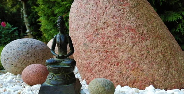 Japon tarzı bir bahçede bronz Buda heykelciği