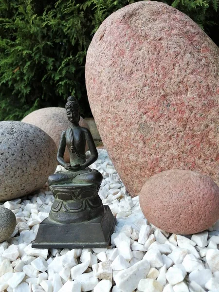 Japon tarzı bir bahçede bronz Buda heykelciği