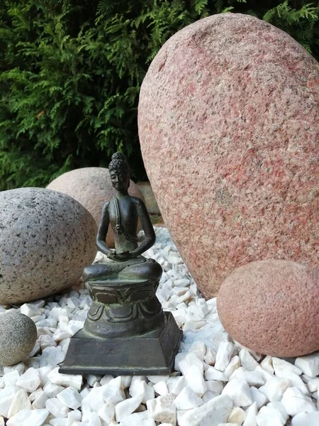 Japon tarzı bir bahçede bronz Buda heykelciği