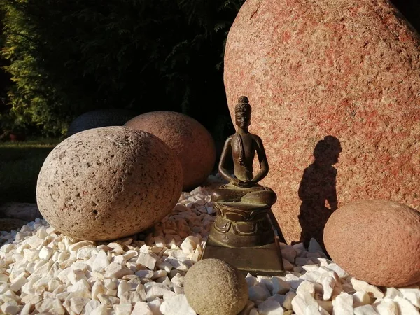 Japon tarzı bir bahçede bronz Buda heykelciği