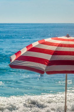 Kırmızı ve beyaz çizgili plaj şemsiyesi ile Blue Sea
