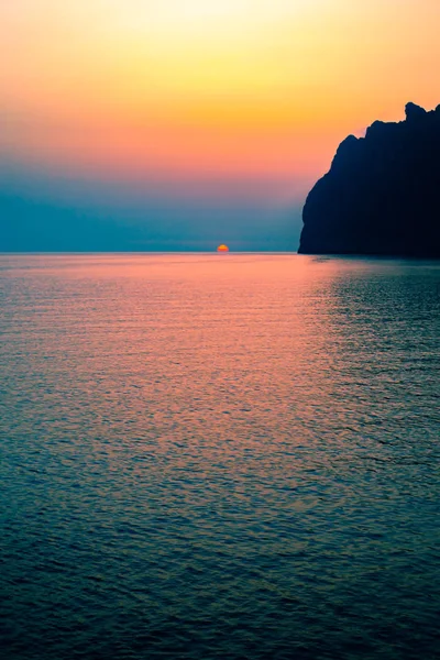 Vibrant Sunrise Over Tranquil Sea With Dramatic Cliffs