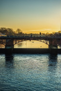 Glasgow İskoçya 'da Clyde Nehri' nin karşısındaki köprüde Güneşli bir kış sabahında Silhouetted Rowers ile
