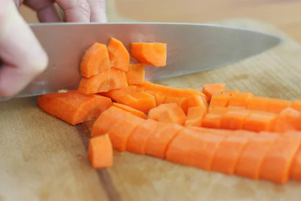 chief chopping fresh carrot on wooden board