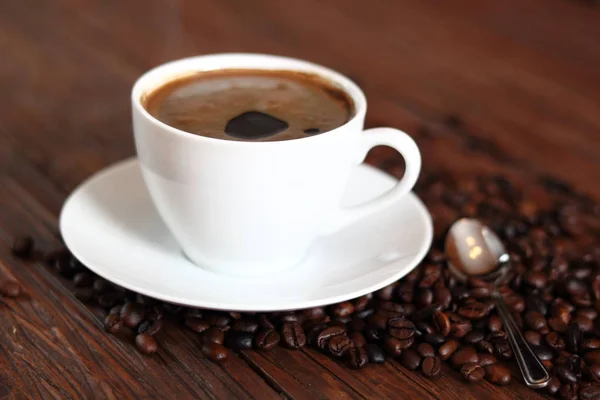 一杯のコーヒーと木の板のテーブルの上のコーヒー豆 — ストック写真