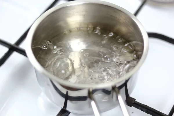煤气炉牛奶锅中的煮沸水 — 图库照片