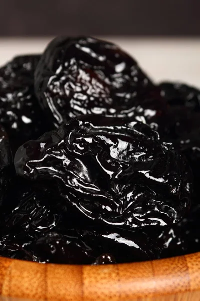 pile of prunes in wooden bowl, close up shot