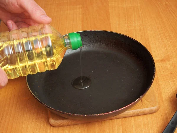 Pouring vegetable oil into frying pan. Making yeast pancakes (crepes).