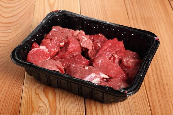 Diced beef casserole steak in disposable plastic packing box.