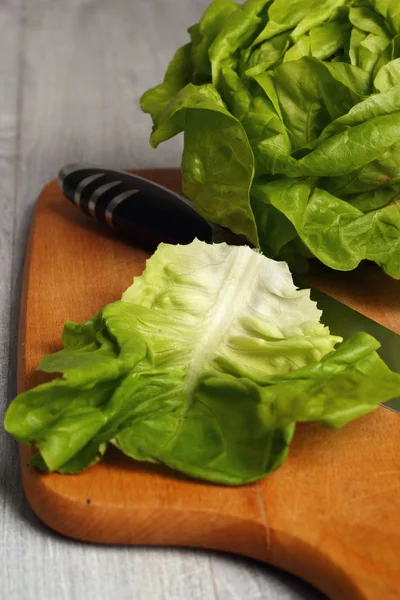 Butter lettuce with knife on kitchen board