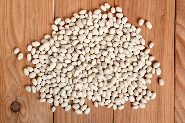 Navy beans at wooden plank background