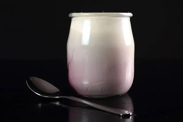酸奶与果酱在打开小玻璃瓶与勺子在黑色背景 — 图库照片